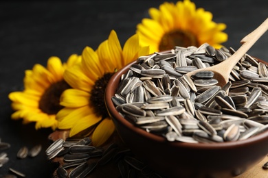 Raw sunflower seeds and flowers on table, closeup