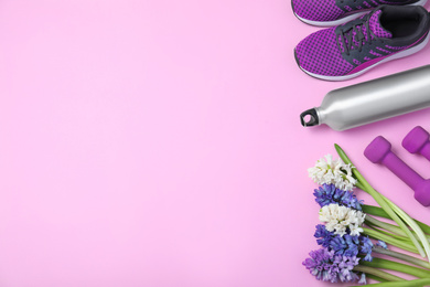 Photo of Flat lay composition with spring flowers and sports items on pink background. Space for text