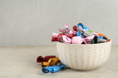 Photo of Candies in colorful wrappers on light beige table, space for text