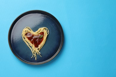 Photo of Heart made with spaghetti and sauce on light blue background, top view. Space for text