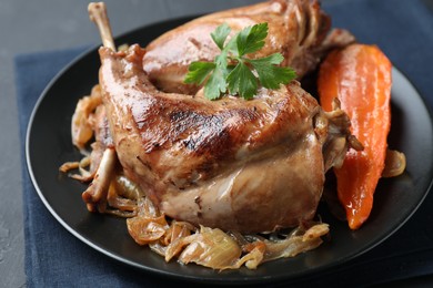 Photo of Tasty cooked rabbit meat with vegetables and parsley on table, closeup