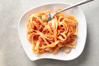 Plate with delicious pasta bolognese on grey background, top view