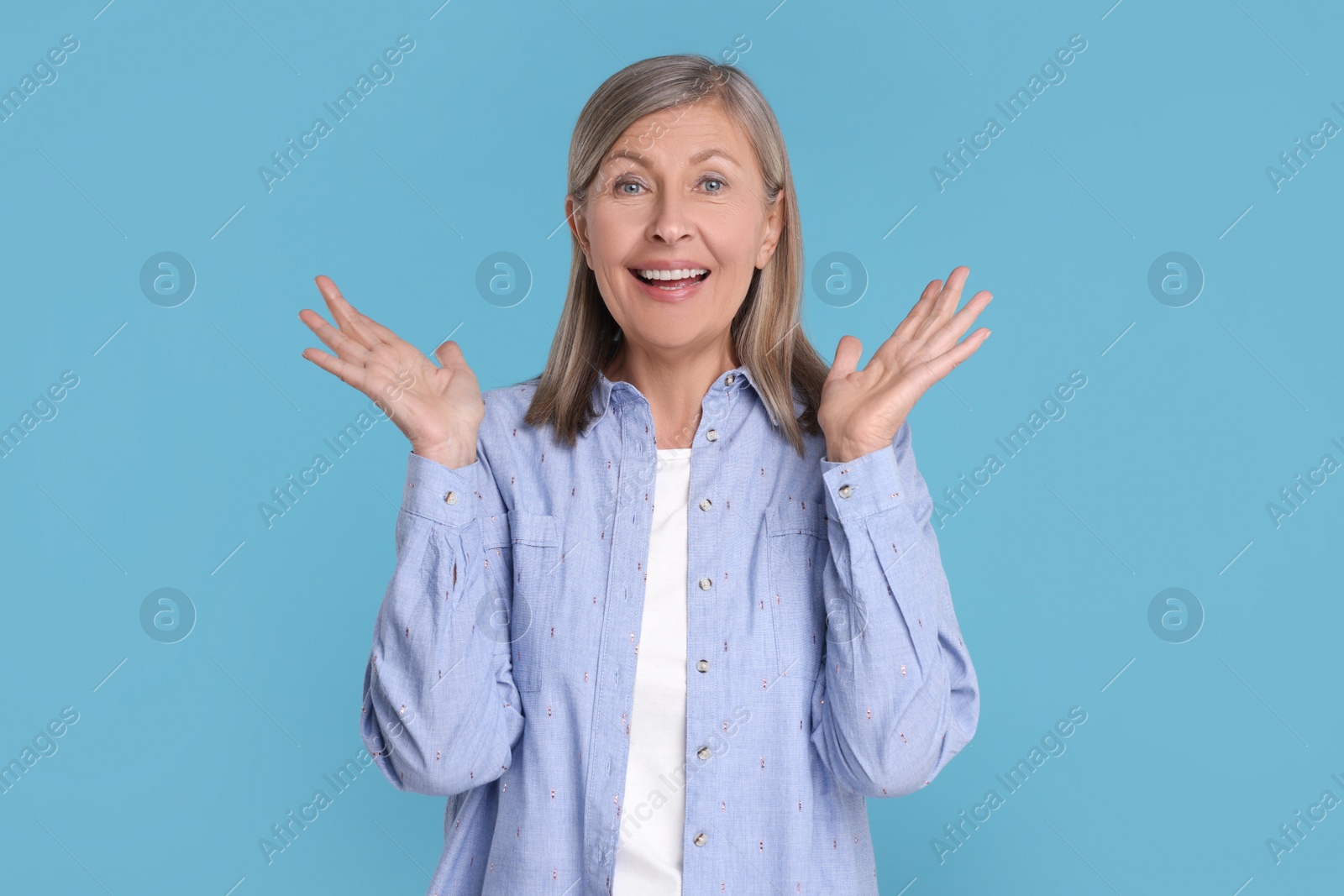 Photo of Portrait of happy surprised senior woman on light blue background