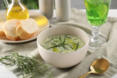 Photo of Delicious cream soup with tarragon, spices and potato in bowl on table