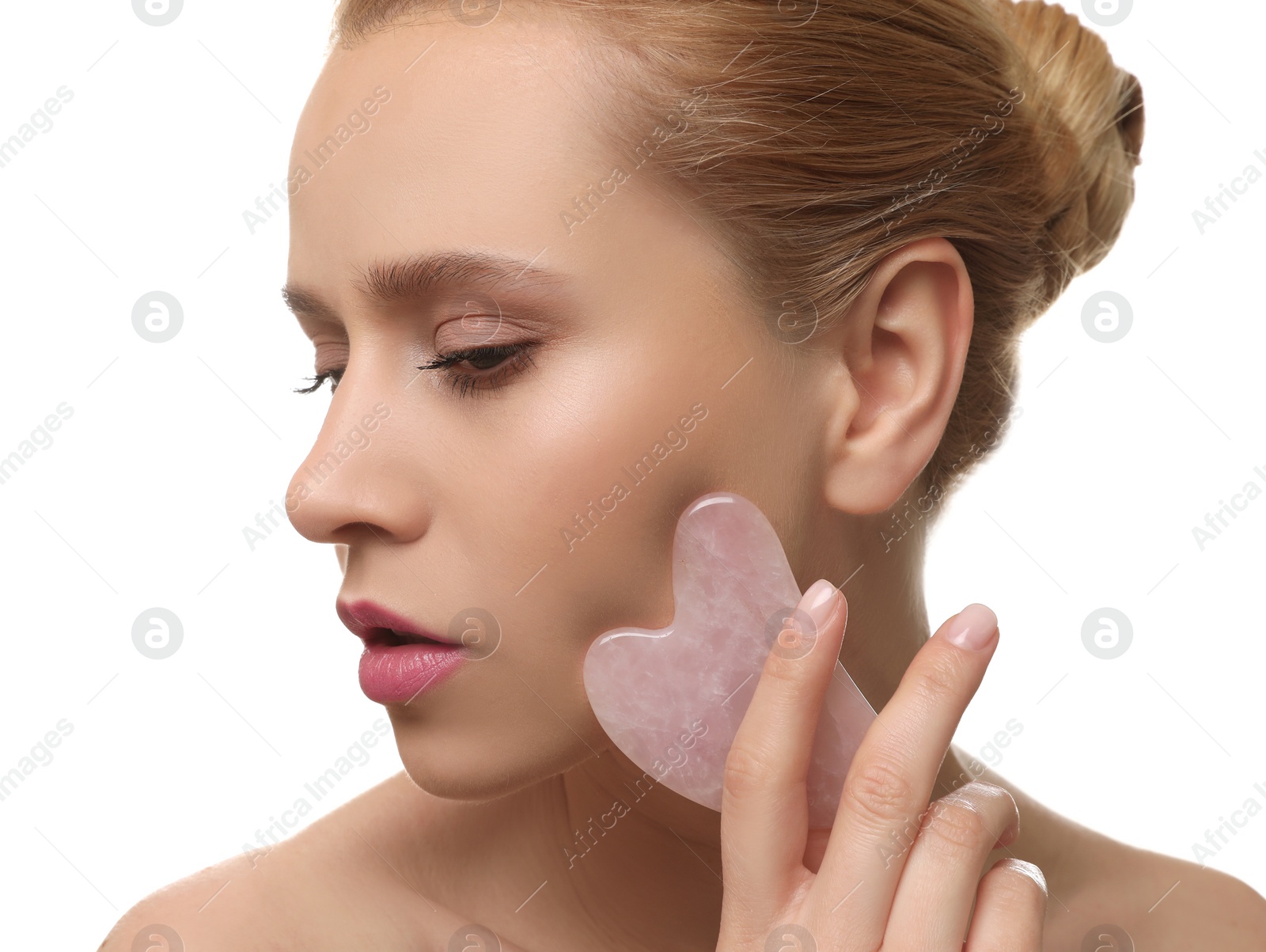 Photo of Beautiful young woman doing facial massage with gua sha tool on white background, closeup