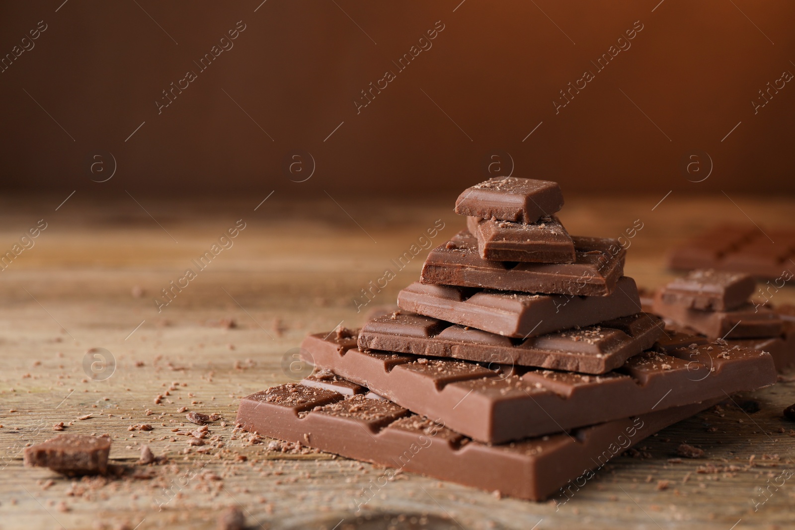 Photo of Pieces and crumbs of tasty chocolate bars on wooden table. Space for text