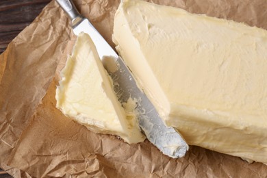 Photo of Tasty homemade butter and knife on parchment, closeup