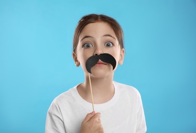 Photo of Cute little girl with fake mustache on turquoise background