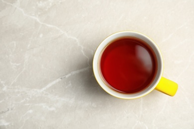 Ceramic cup of black tea on gray table, top view