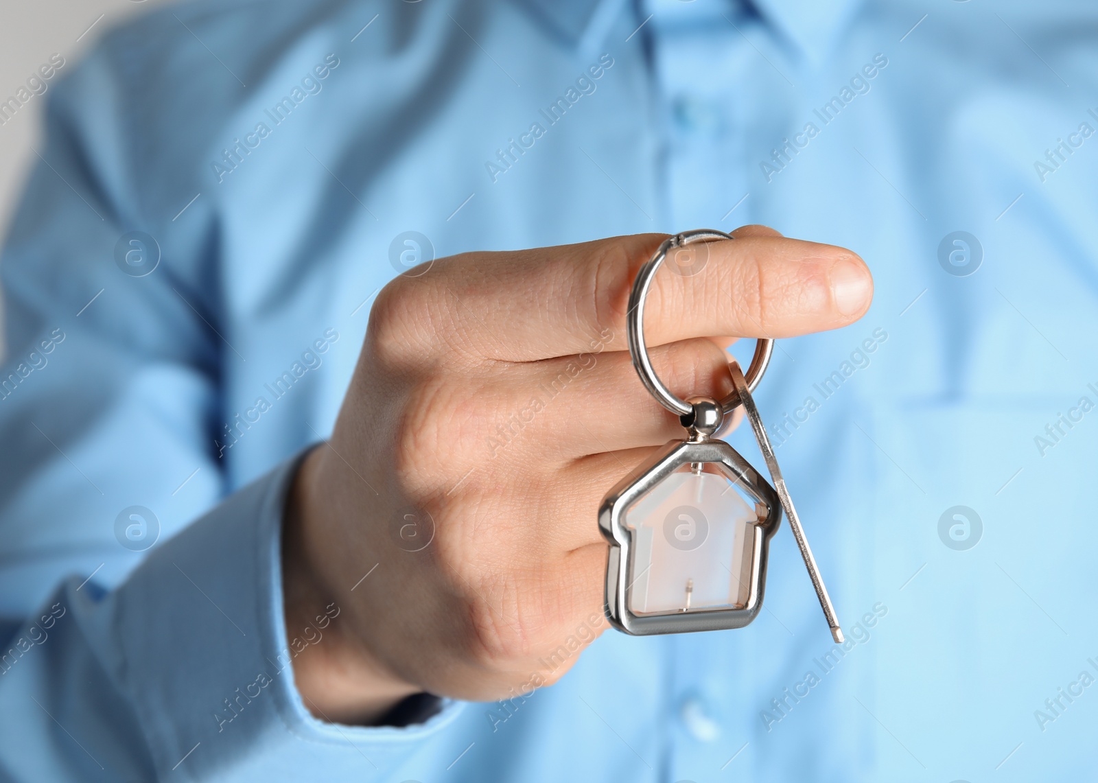 Photo of Young man holding house key with trinket, closeup