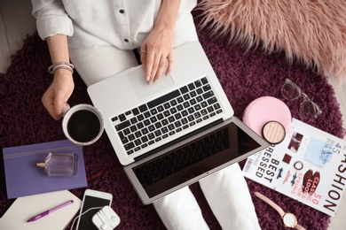 Female blogger with laptop and cup of coffee indoors, top view