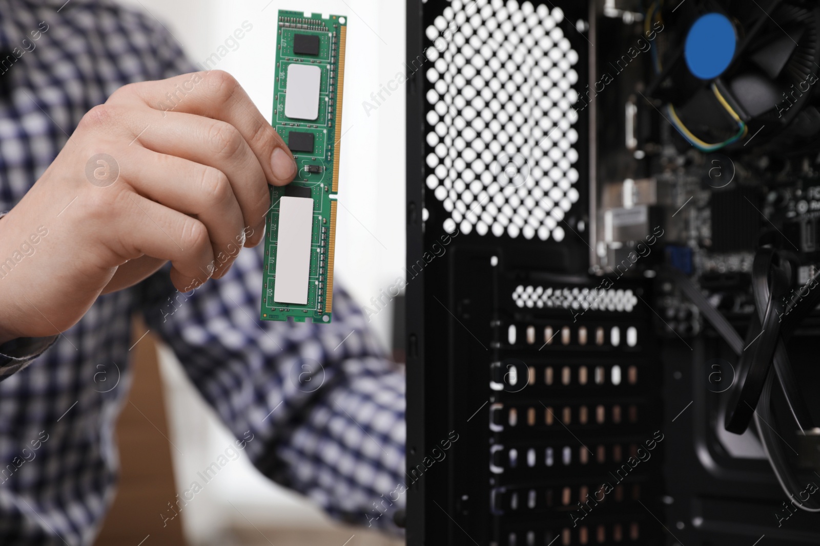 Photo of Male technician putting RAM chip into system unit, closeup. Computer repair