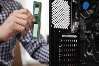 Male technician putting RAM chip into system unit, closeup. Computer repair