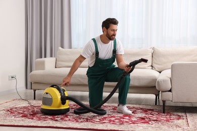 Photo of Dry cleaner's employee with vacuum cleaner on carpet in room