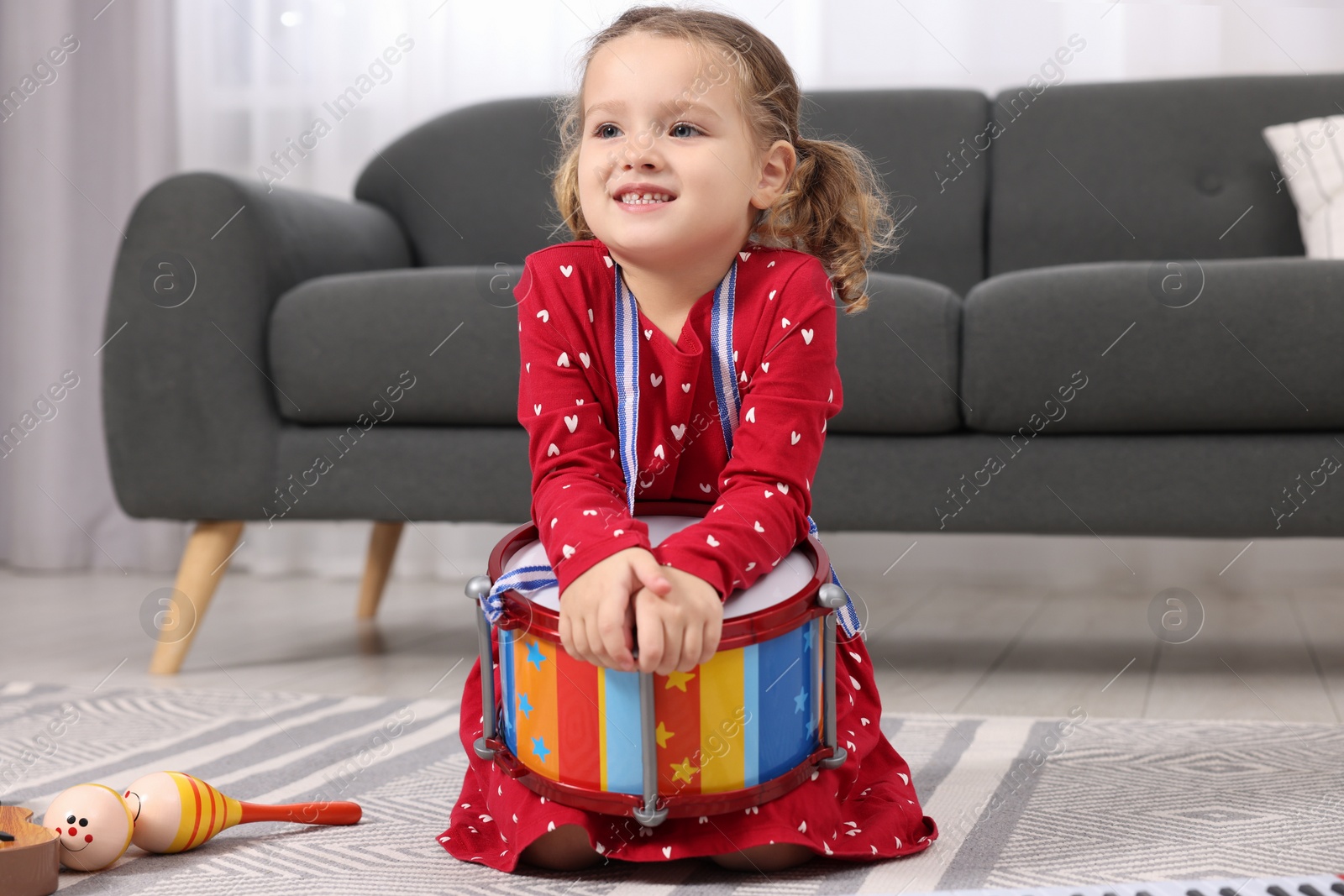 Photo of Little girl playing toy drum at home