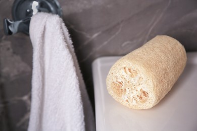 Photo of Natural loofah sponge on washbasin in bathroom, closeup
