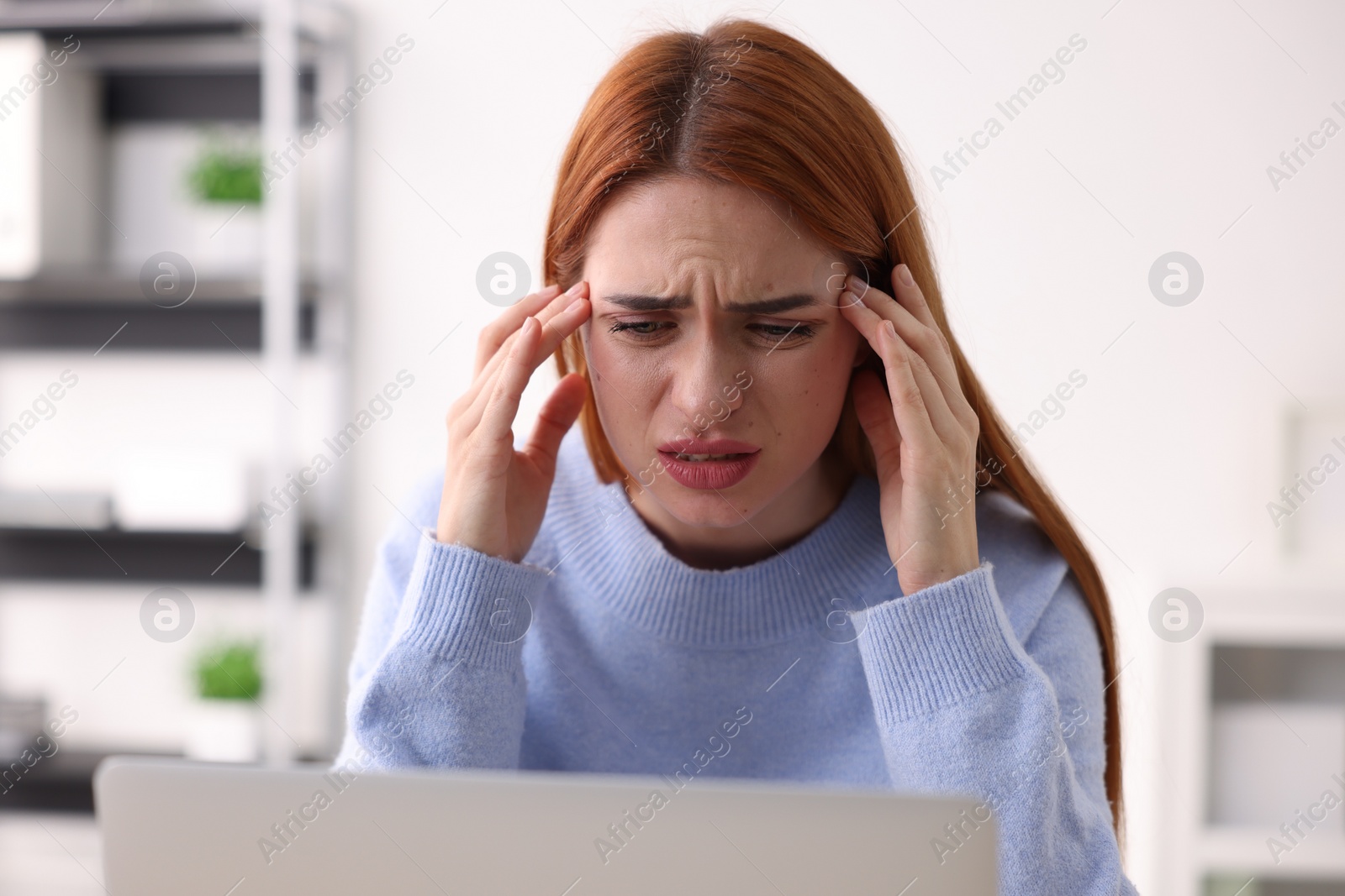 Photo of Woman suffering from headache at workplace in office