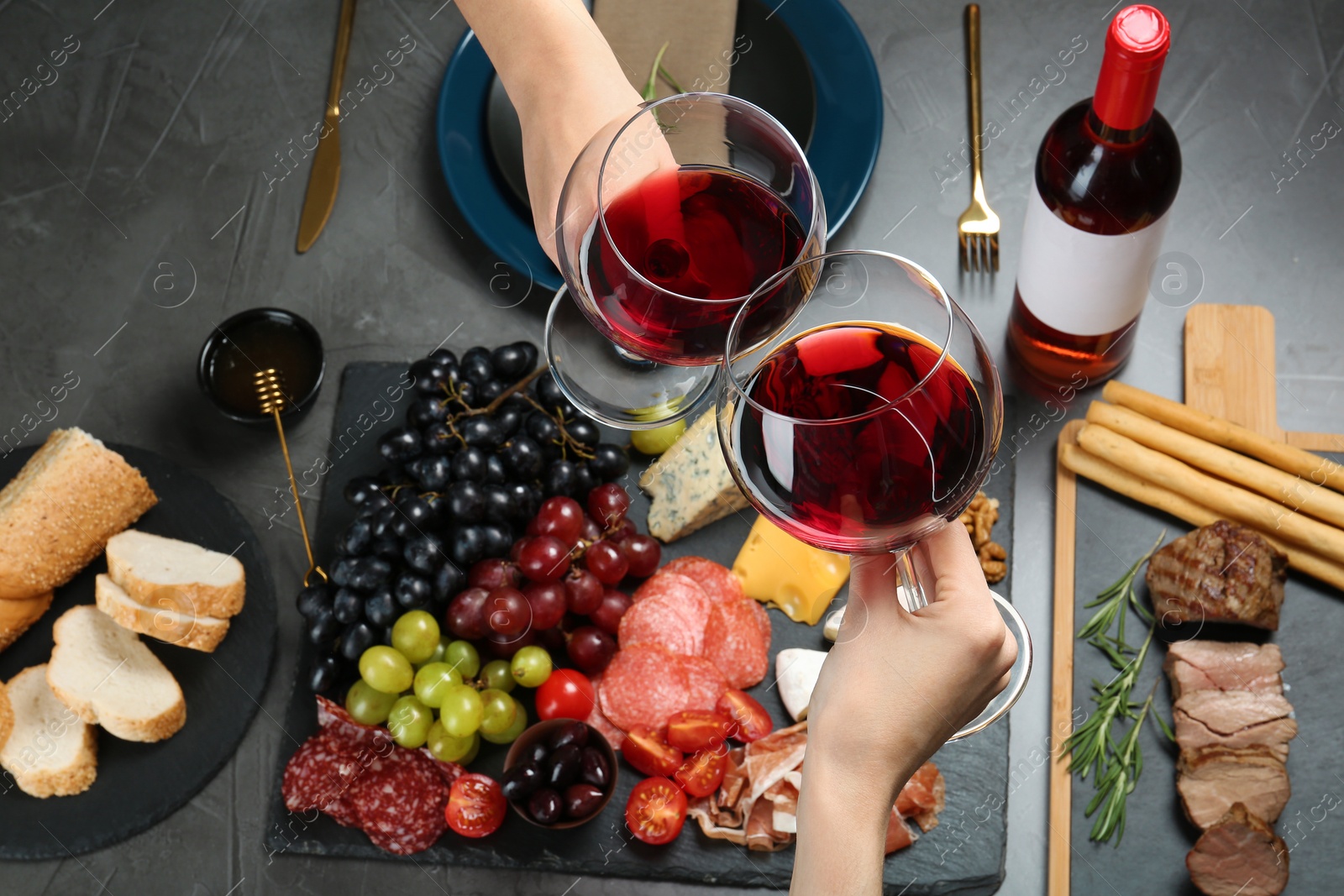 Photo of Women holding glasses of red wine over table with snacks, above view