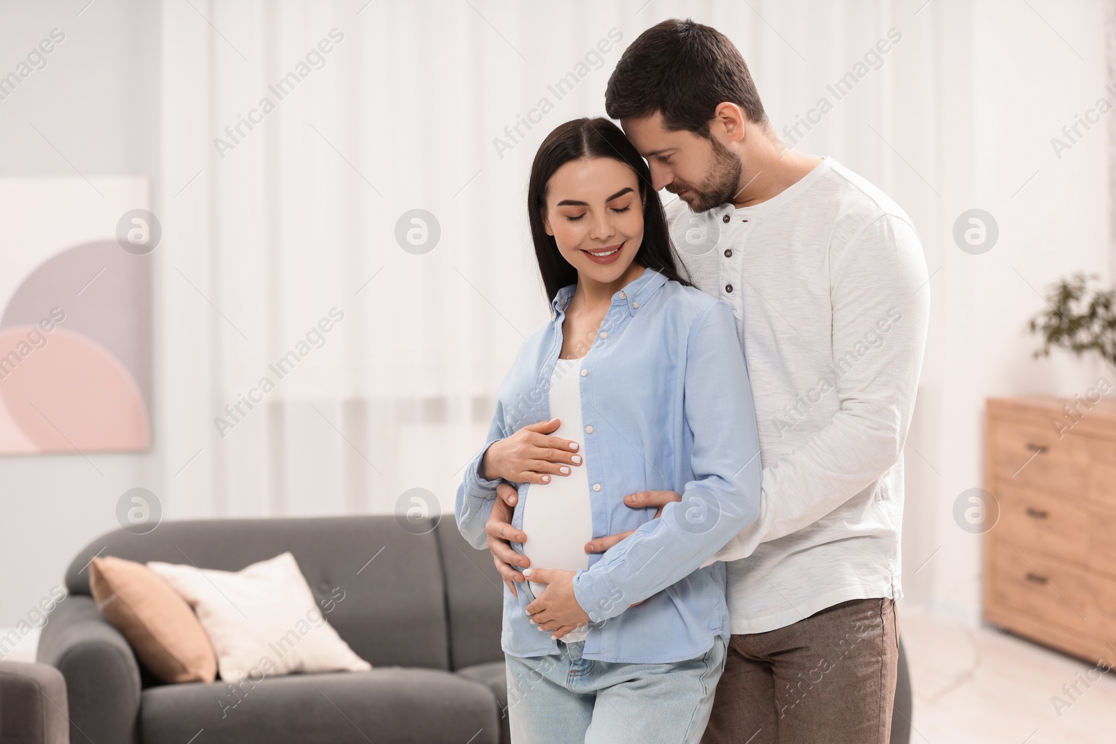 Photo of Happy pregnant woman with her husband at home, space for text