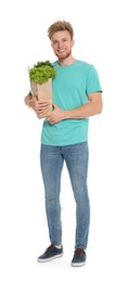 Photo of Young man with bag of fresh vegetables on white background