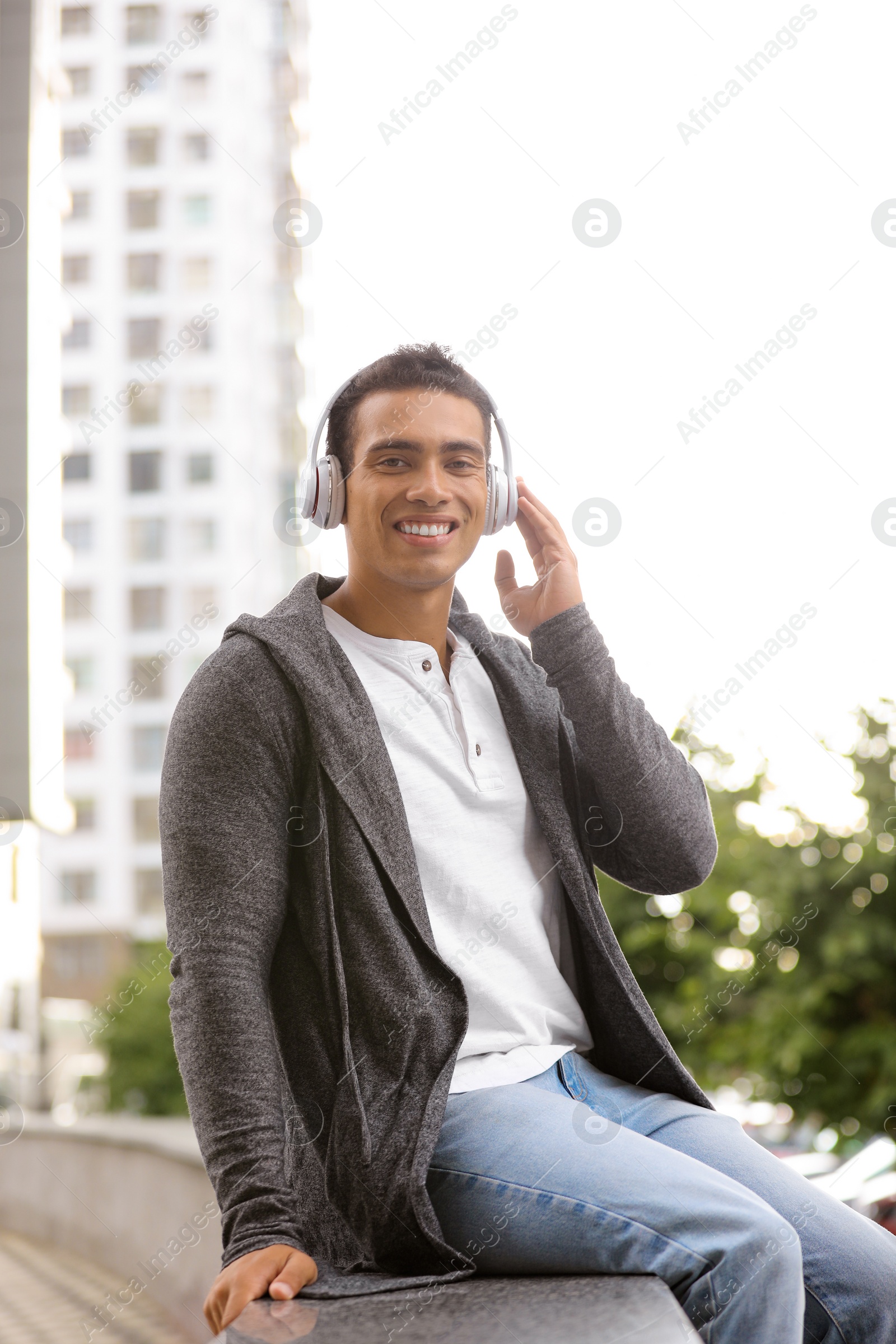 Photo of Handsome young African-American man with headphones listening to music on city street