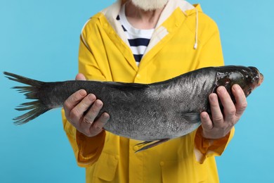 Photo of Fisherman with caught fish on light blue background, closeup