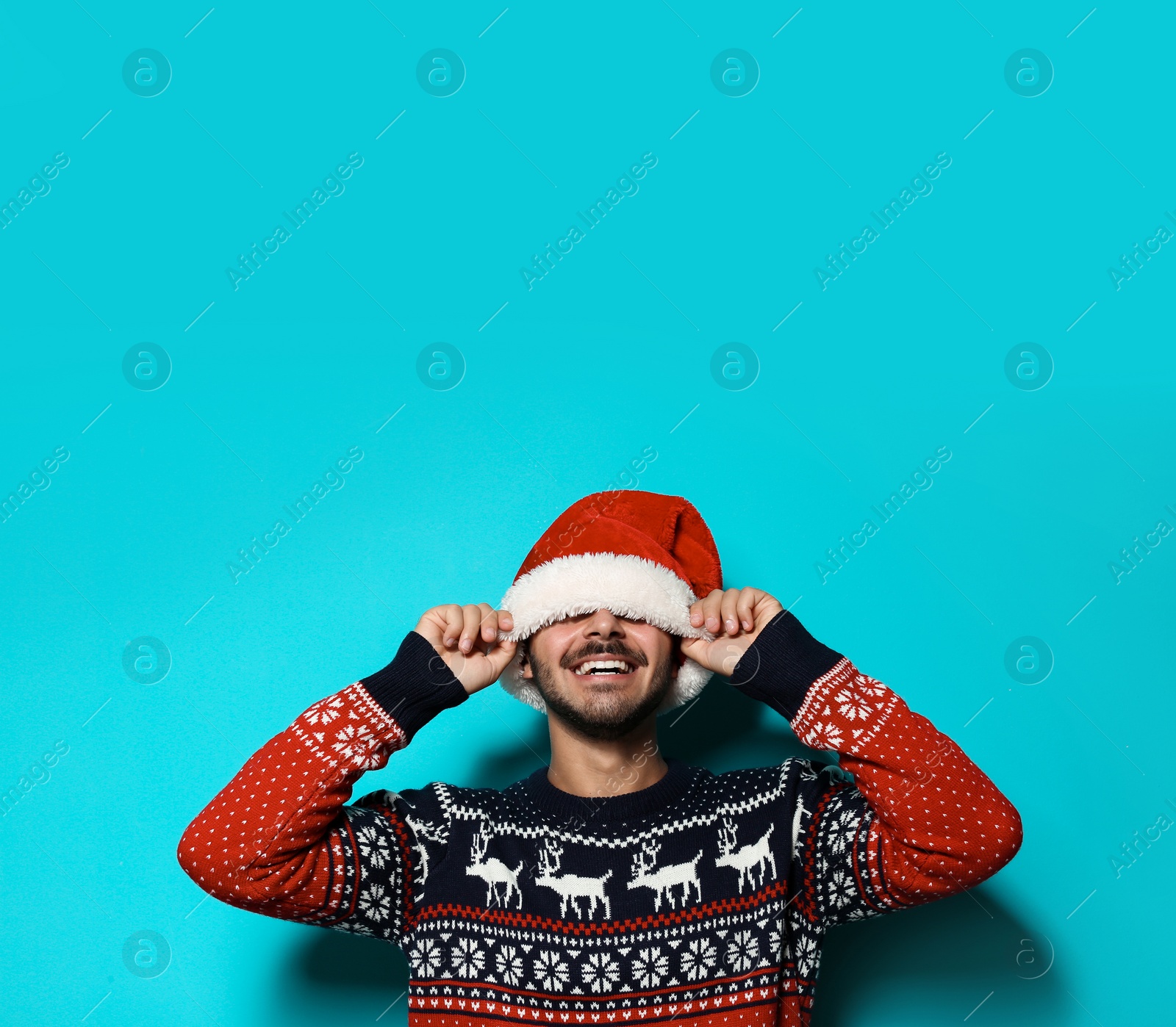 Photo of Young man in Christmas sweater and hat on color background