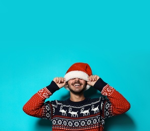 Photo of Young man in Christmas sweater and hat on color background