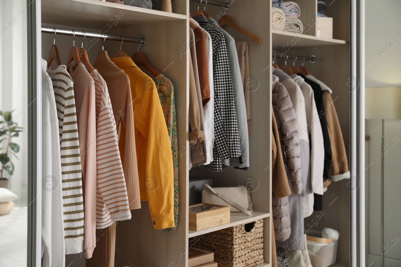 Photo of Wardrobe closet with different stylish clothes, accessories and home stuff in room