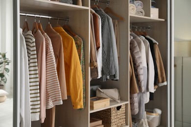 Photo of Wardrobe closet with different stylish clothes, accessories and home stuff in room