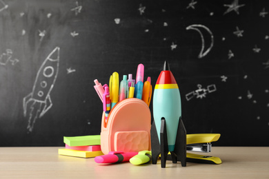 Photo of Bright toy rocket and school supplies on wooden table