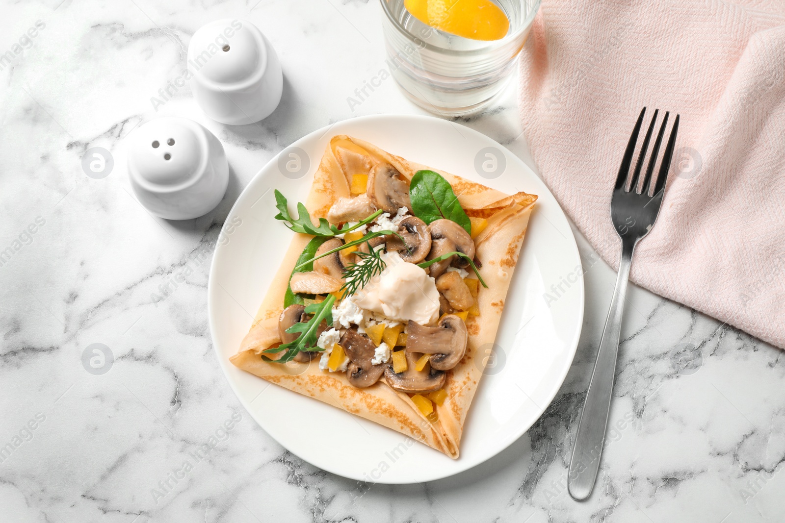 Photo of Delicious breakfast with thin pancakes on marble table, flat lay