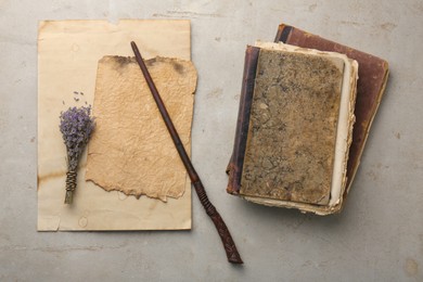 Photo of Magic wand, lavender flowers, old books and papers on light textured background, flat lay