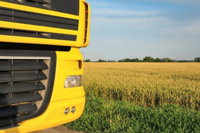 Photo of Modern yellow truck on country road, closeup. Space for text