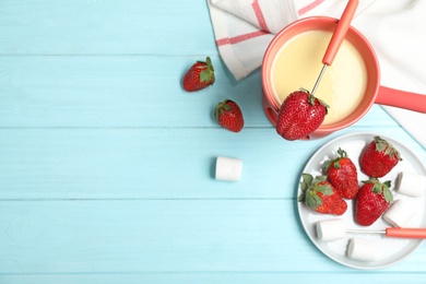 Chocolate fondue with strawberries and marshmallow on wooden table, flat lay. Space for text