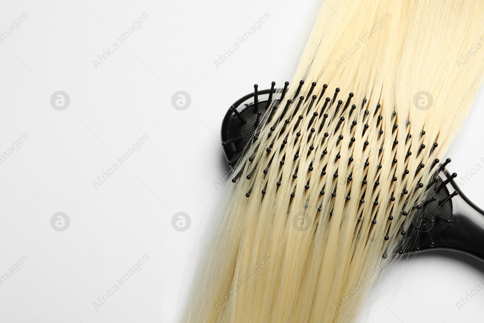 Photo of Stylish brush with blonde hair strand on white background, top view