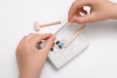 Photo of Child playing with Excavation kit at white table, above view. Educational toy for motor skills