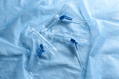 Photo of Anoscopes on light blue fabric, flat lay. Hemorrhoid treatment