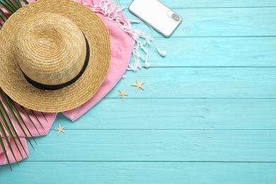 Flat lay composition with beach accessories on light blue wooden background, space for text