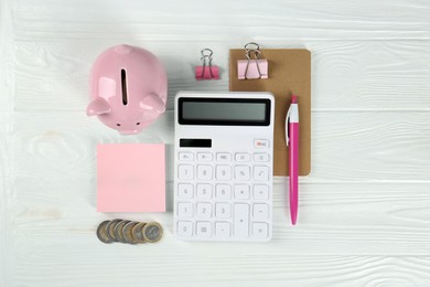 Calculator, coins, piggy bank, notebook, binder clips and pen on white wooden table, flat lay. Retirement concept