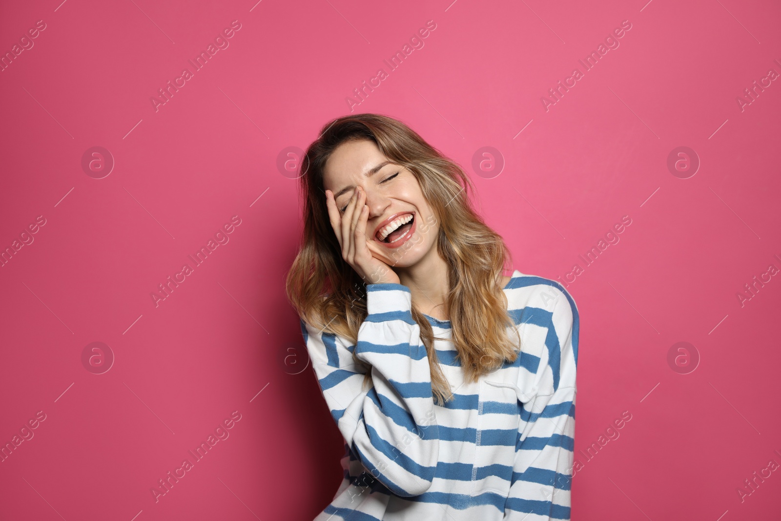 Photo of Cheerful young woman laughing on pink background