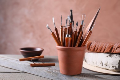 Clay and set of crafting tools on grey wooden table in workshop, closeup