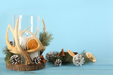 Stylish holder with burning candle and Christmas decor on light blue wooden table. Space for text