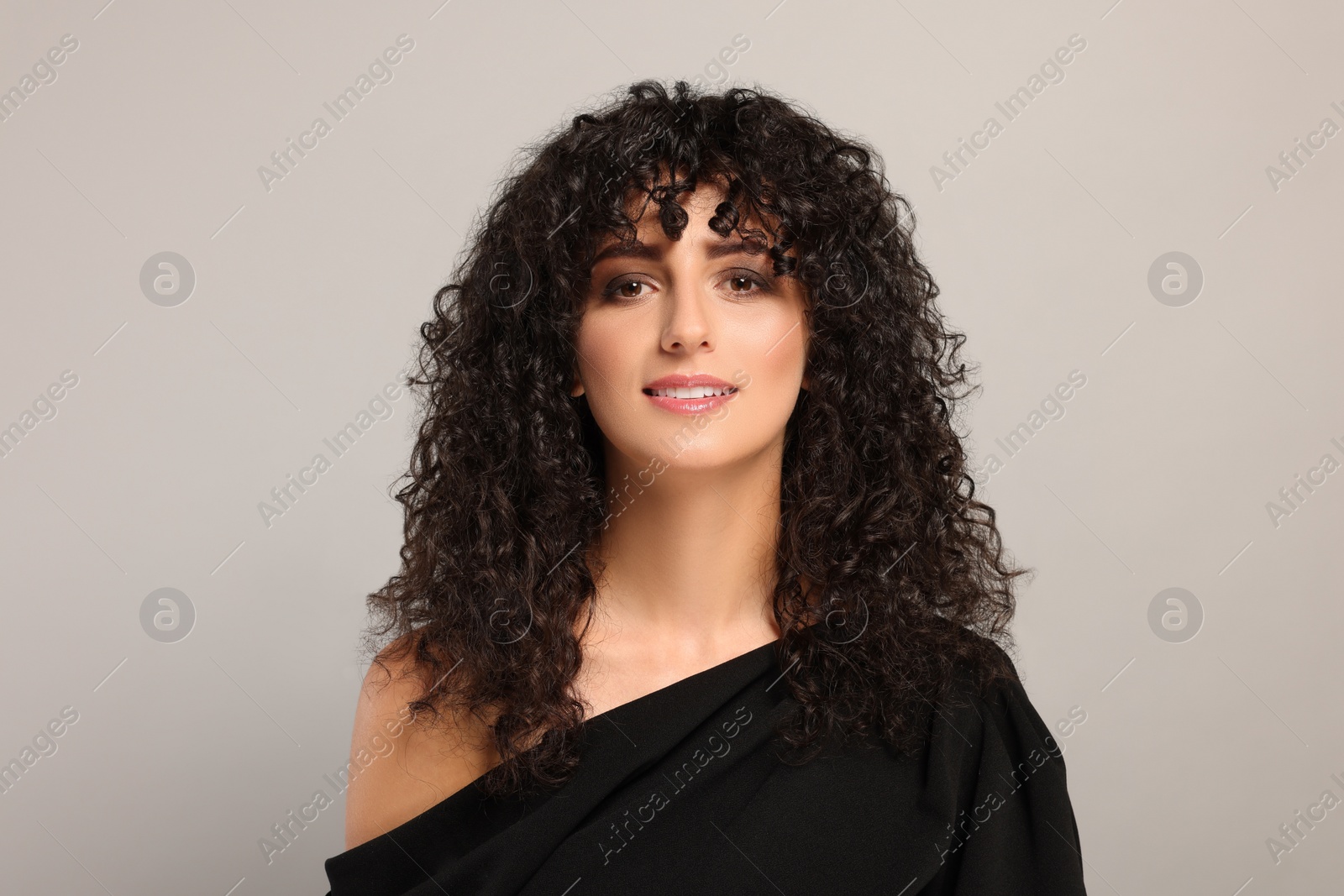 Photo of Beautiful young woman with long curly hair on light grey background