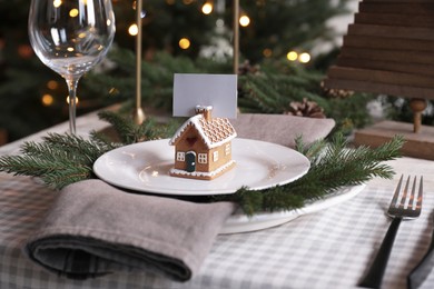 Photo of Festive place setting with beautiful dishware, cutlery and gingerbread house card holder for Christmas dinner on wooden table