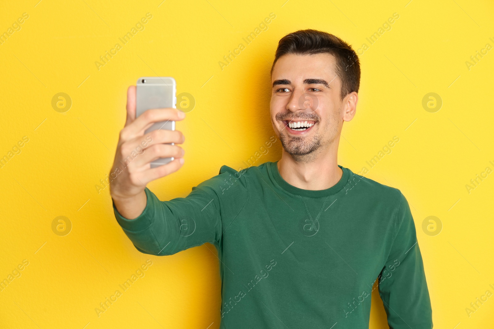 Photo of Young handsome man taking selfie against color background