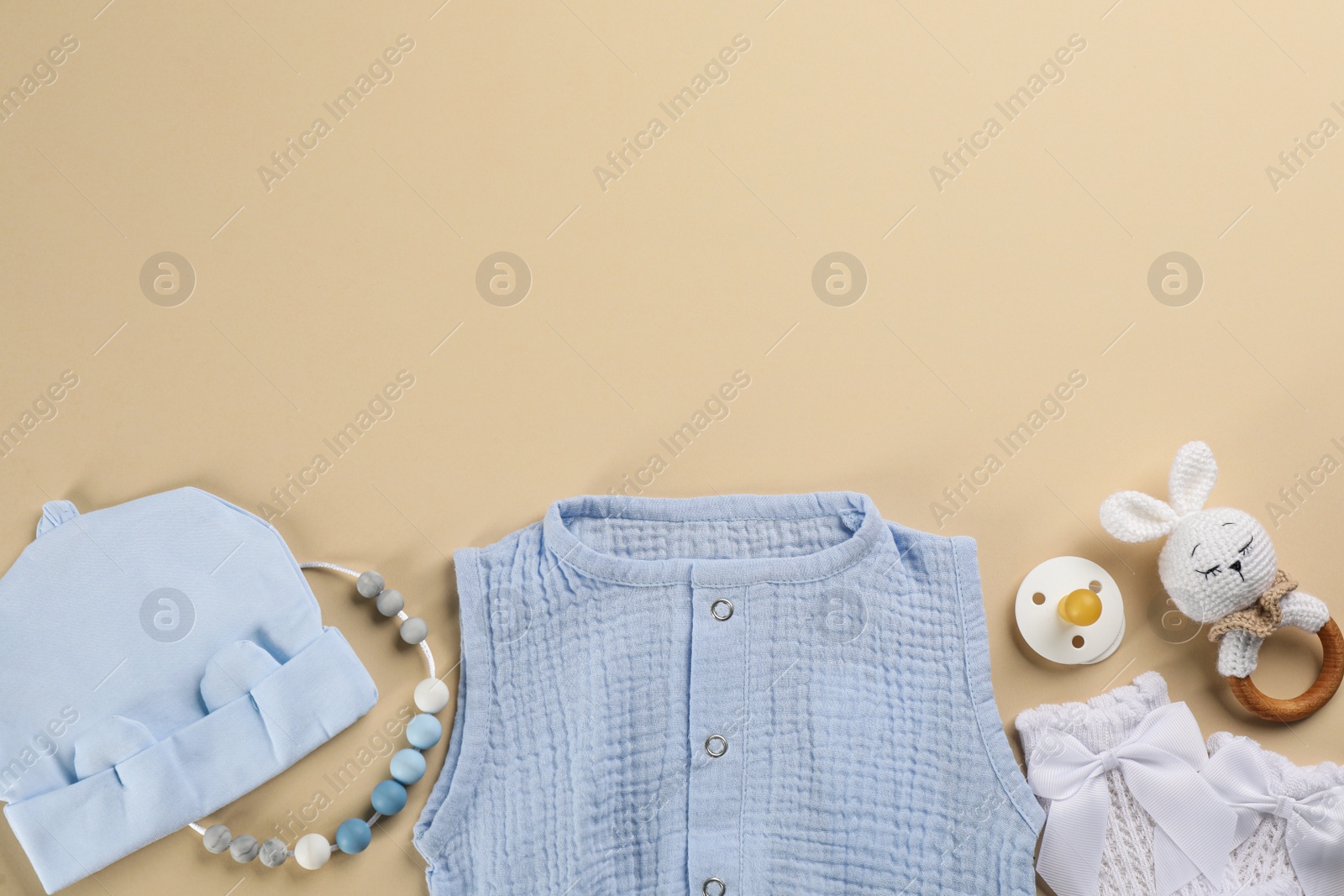 Photo of Flat lay composition with baby clothes and accessories beige background, space for text