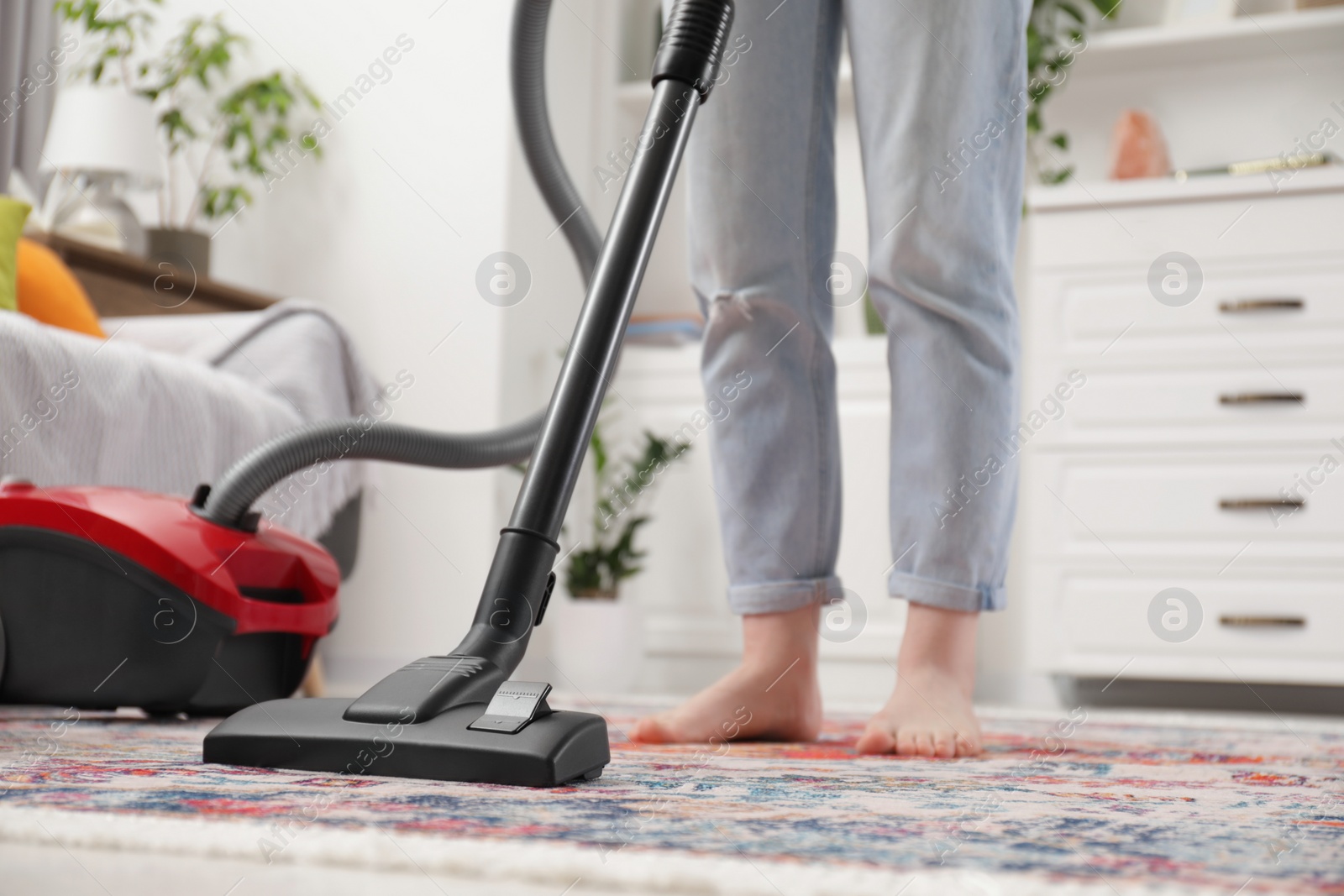 Photo of Woman cleaning carpet with vacuum cleaner at home, closeup