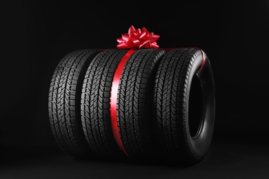 Photo of Winter tires with red ribbon on black background