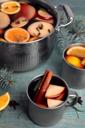 Photo of Tasty mulled wine with spices on blue wooden table